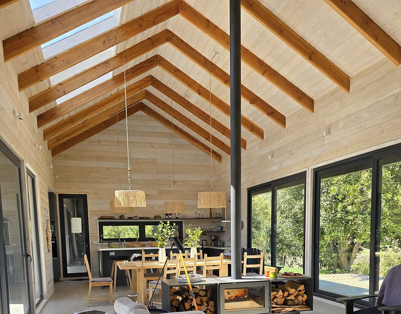 Interior terminado de una casa de panel SIP, con cielo de madera a la vista y estufa a leña
